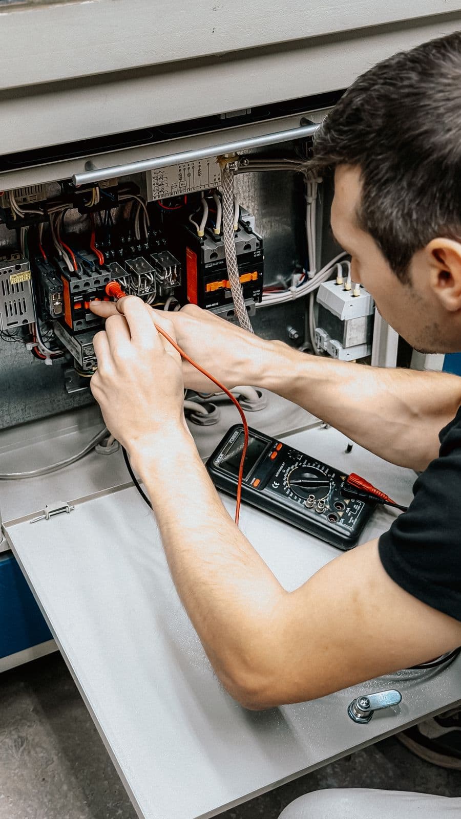 Electrician testing electrical panel connections with a multimeter